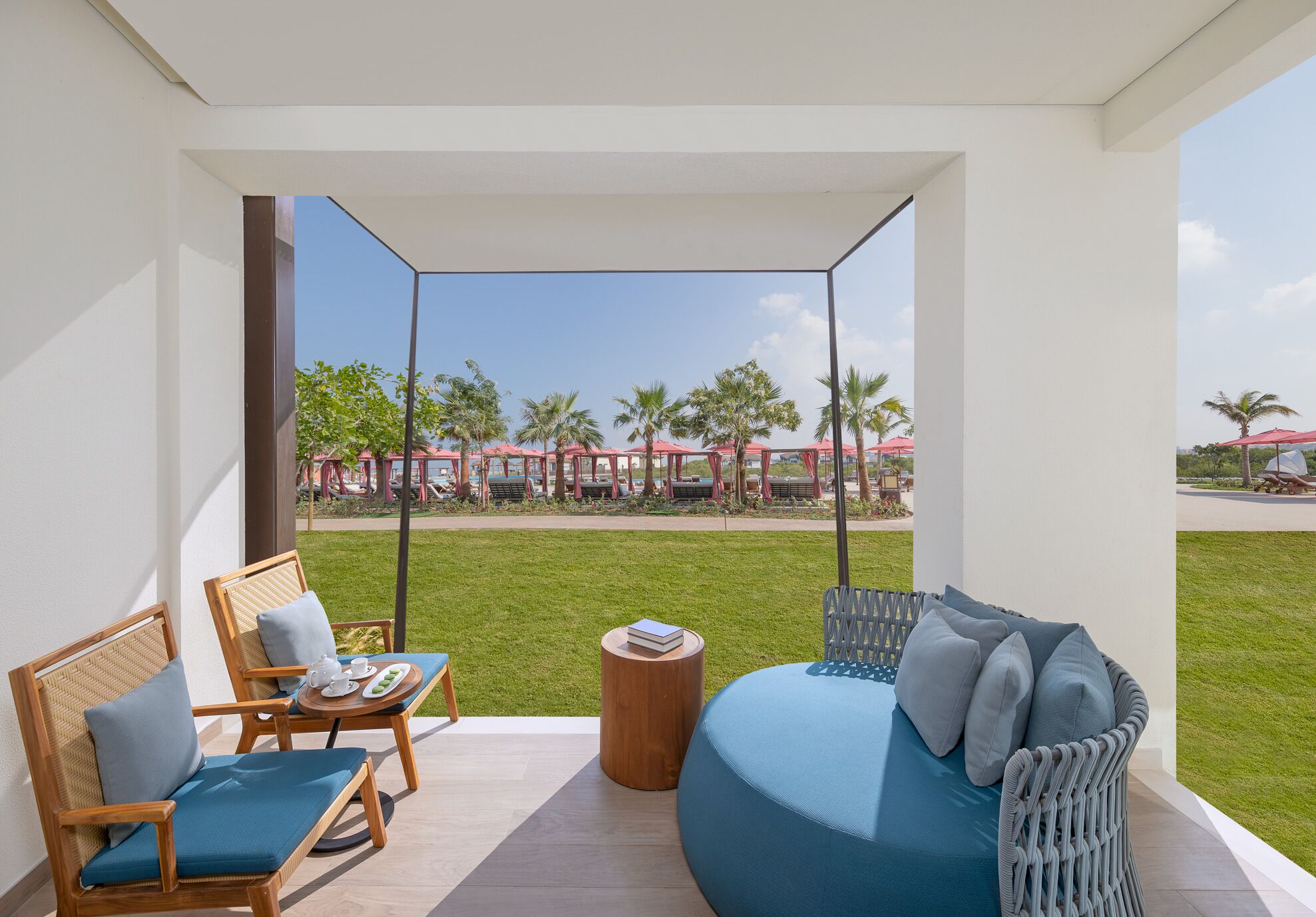 Ein Balkon mit Blick auf einen Poolbereich, eine Sitzecke und ein Sessel mit Tisch.