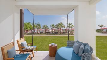Ein Balkon mit Blick auf einen Poolbereich, eine Sitzecke und ein Sessel mit Tisch.