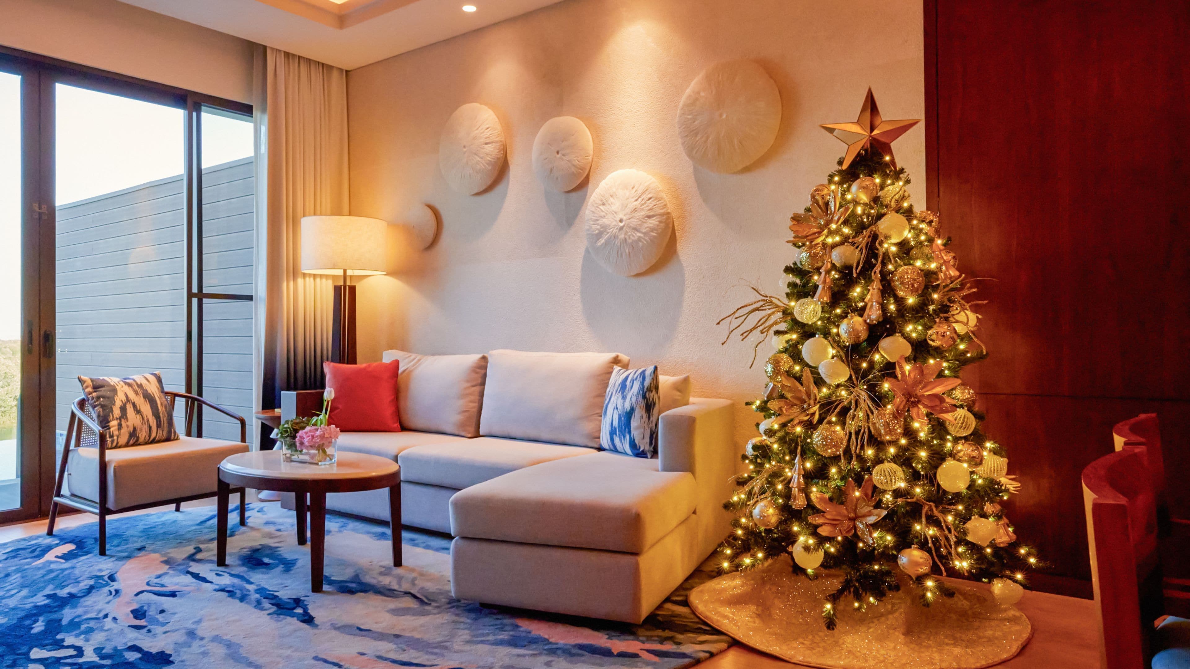 Ein modernes Wohnzimmer mit einer Eckcouch, einem runden Couchtisch und einem Weihnachtsbaum.