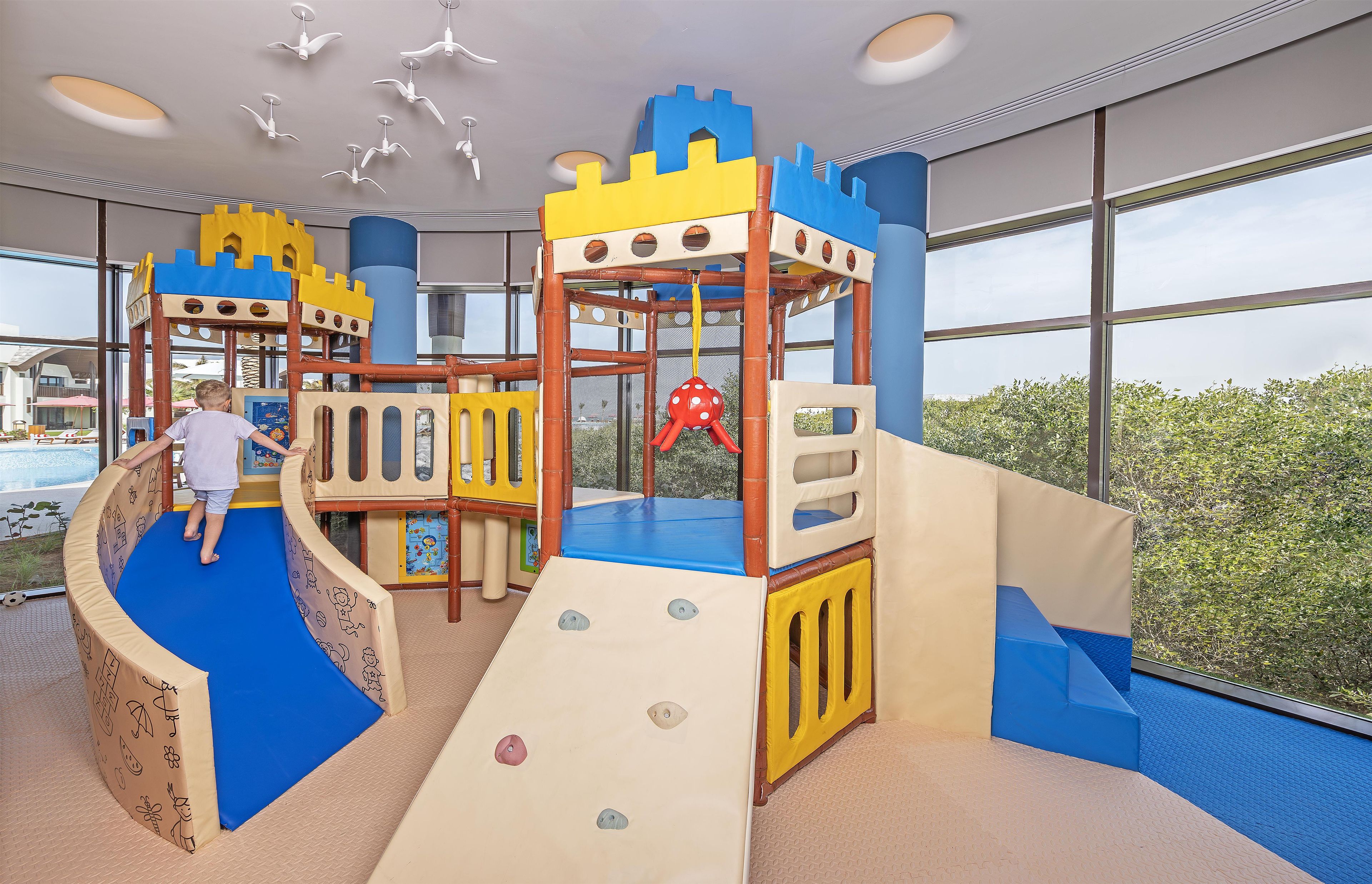 Een kinderspeelplaats met een glijbaan, klimconstructies en een hangend speeltje.