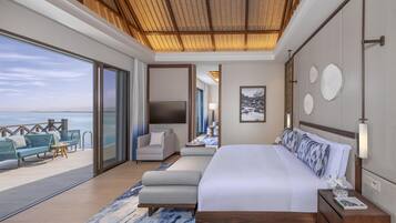 A modern hotel room with a large bed, a seating area with a view of the sea, and a balcony.