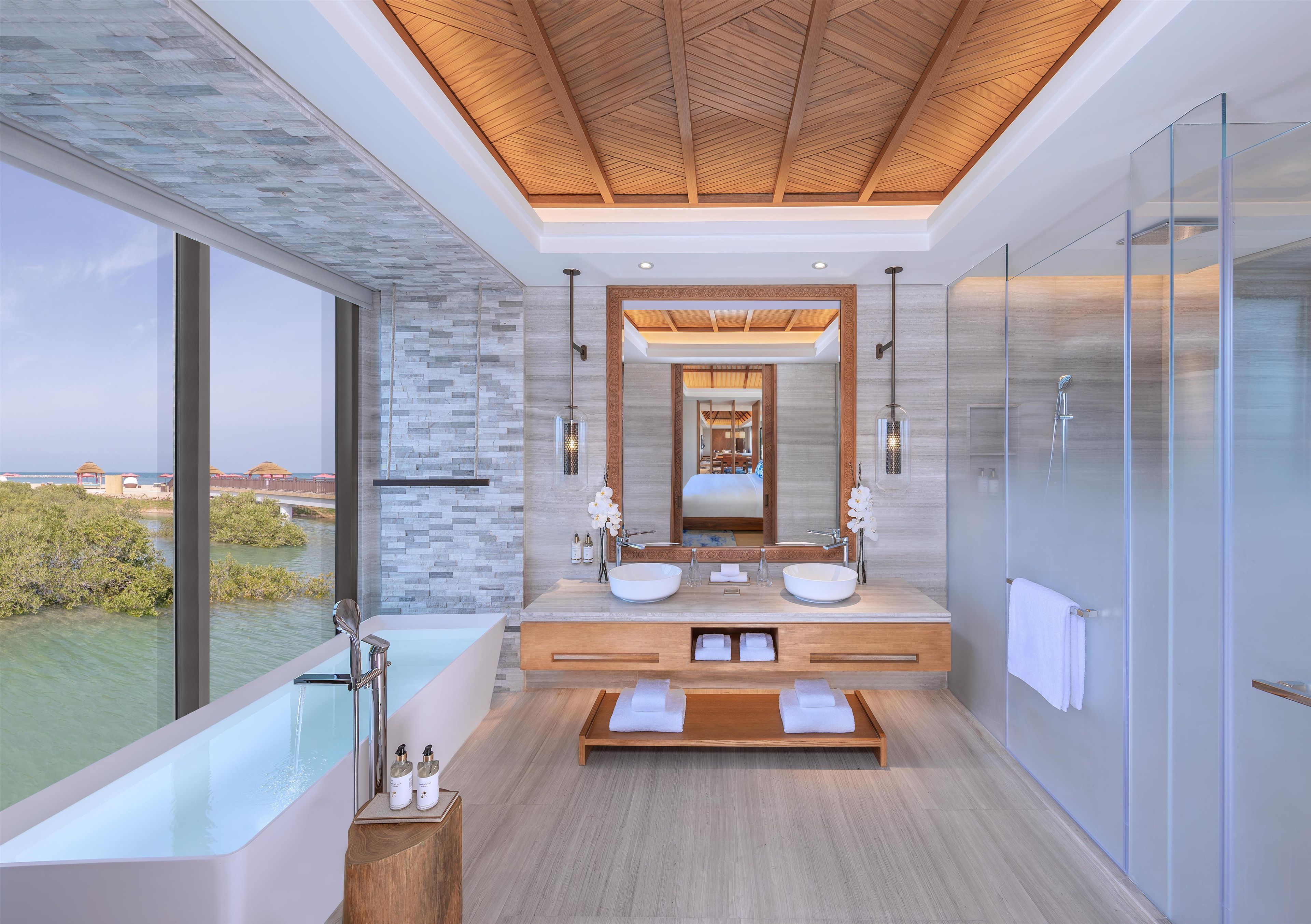 Une salle de bain moderne dotée d’une grande baignoire, de deux vasques et d’une douche à parois de verre.