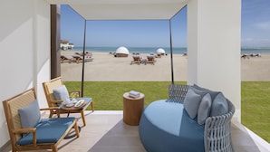 A balcony with a view of the beach, furnished with a sofa, chairs, and a small table. - Anantara Mina Ras Al Khaimah Resort (Ras Al Khaimah)