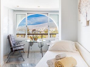 A hotel room with a bed, a seating area with a table, and a large window offering a scenic view. - 512 Parque Santiago II, sea view (Playa de las Américas)