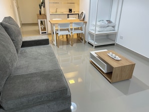 Ein modernes Wohnzimmer mit einem grauen Sofa, einem Holztisch und einem Essbereich mit einem Holztisch und weißen Stühlen.