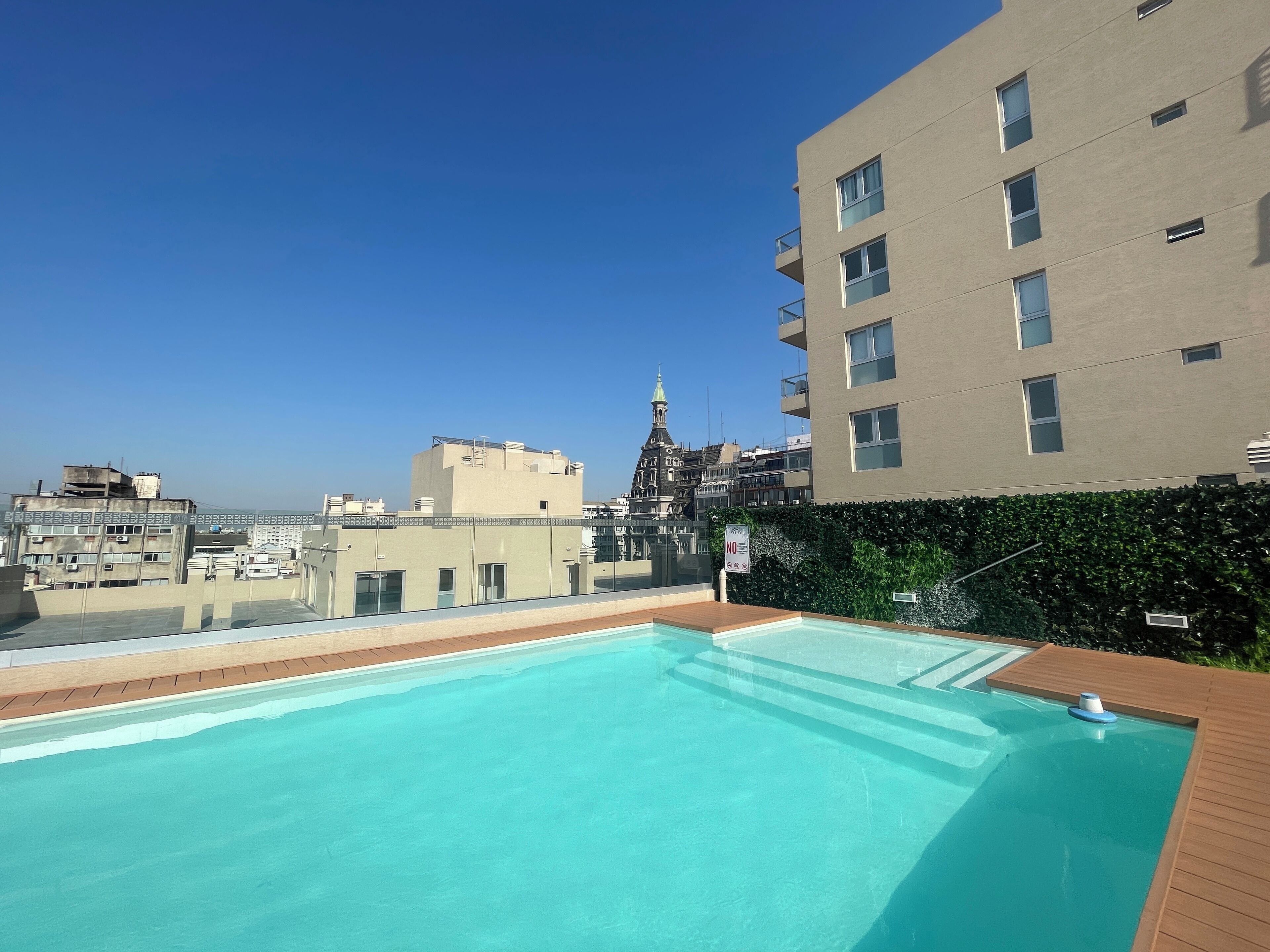A rooftop pool with a clear view of the city skyline and a historic church tower in the background.