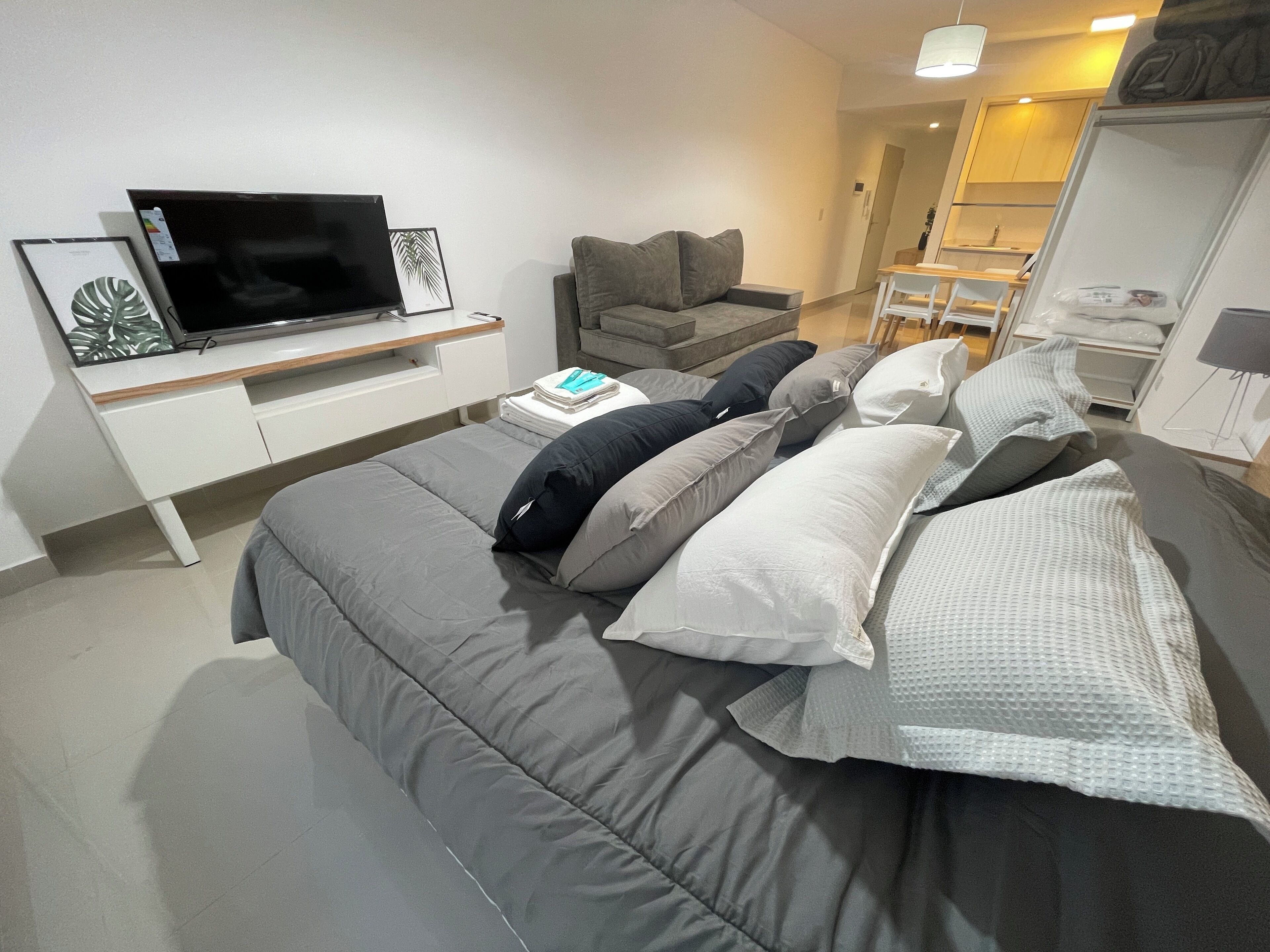 A modern bedroom with a bed, a TV, a desk, and a wardrobe.