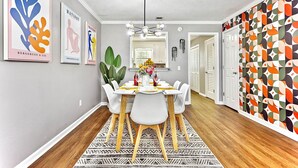 A dining area with a white table, chairs, and a patterned rug.