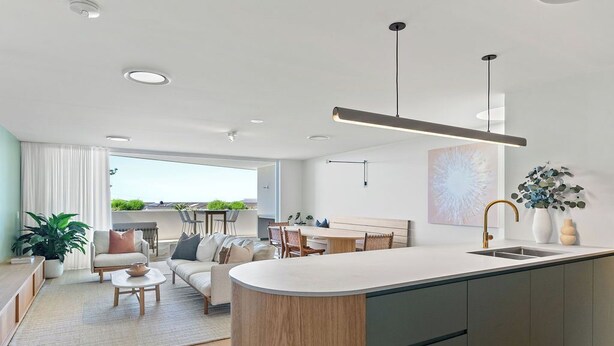 Eine moderne Küche mit Kochinsel, ein Essbereich mit Tisch und Stühlen sowie ein Wohnzimmer mit Sofa und Couchtisch.
