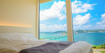 Un dormitorio con un ventanal grande que ofrece vistas al mar, incluyendo un puente y tierra a lo lejos.