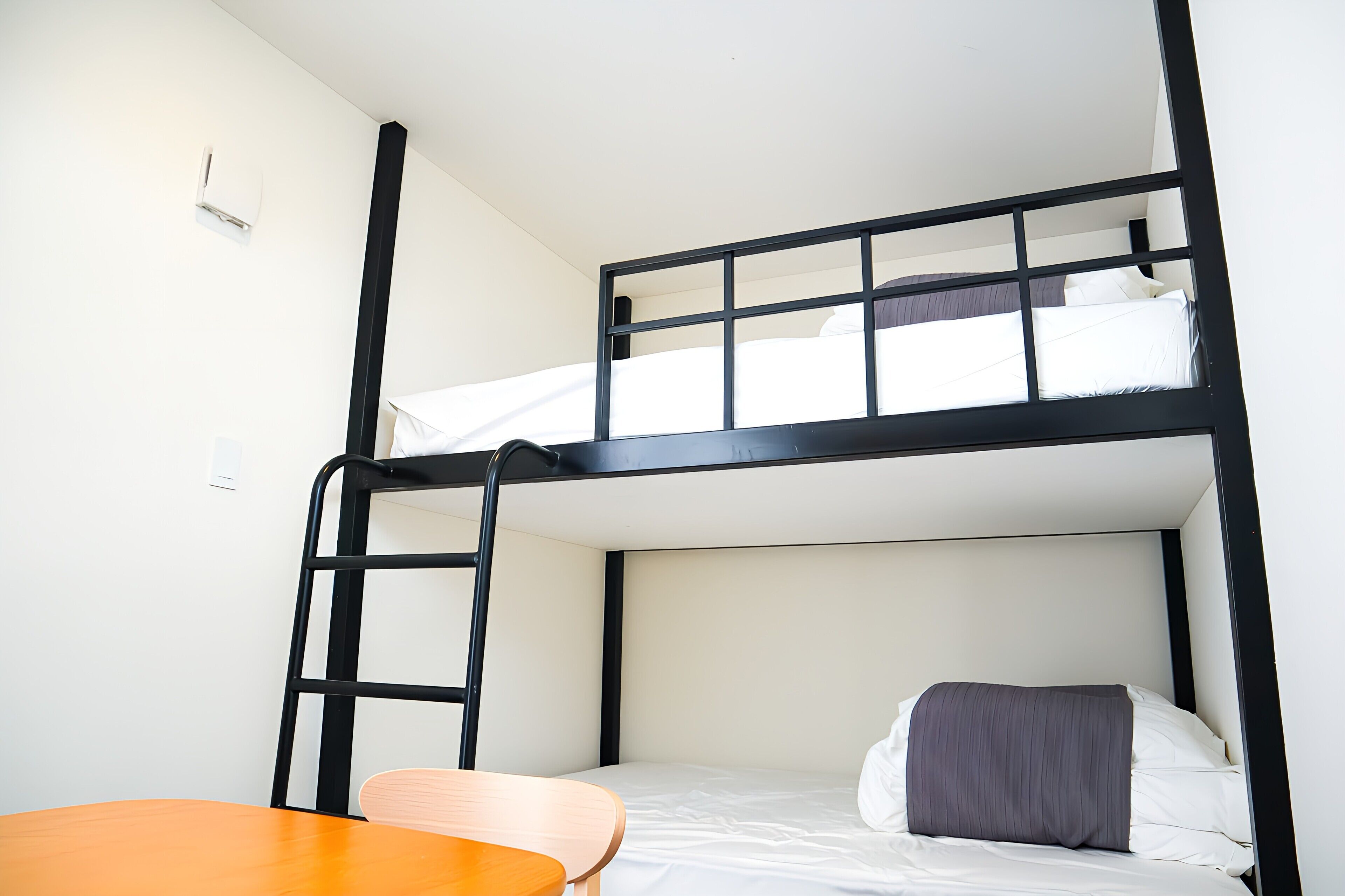 A bunk bed room with a wooden table and a ladder.