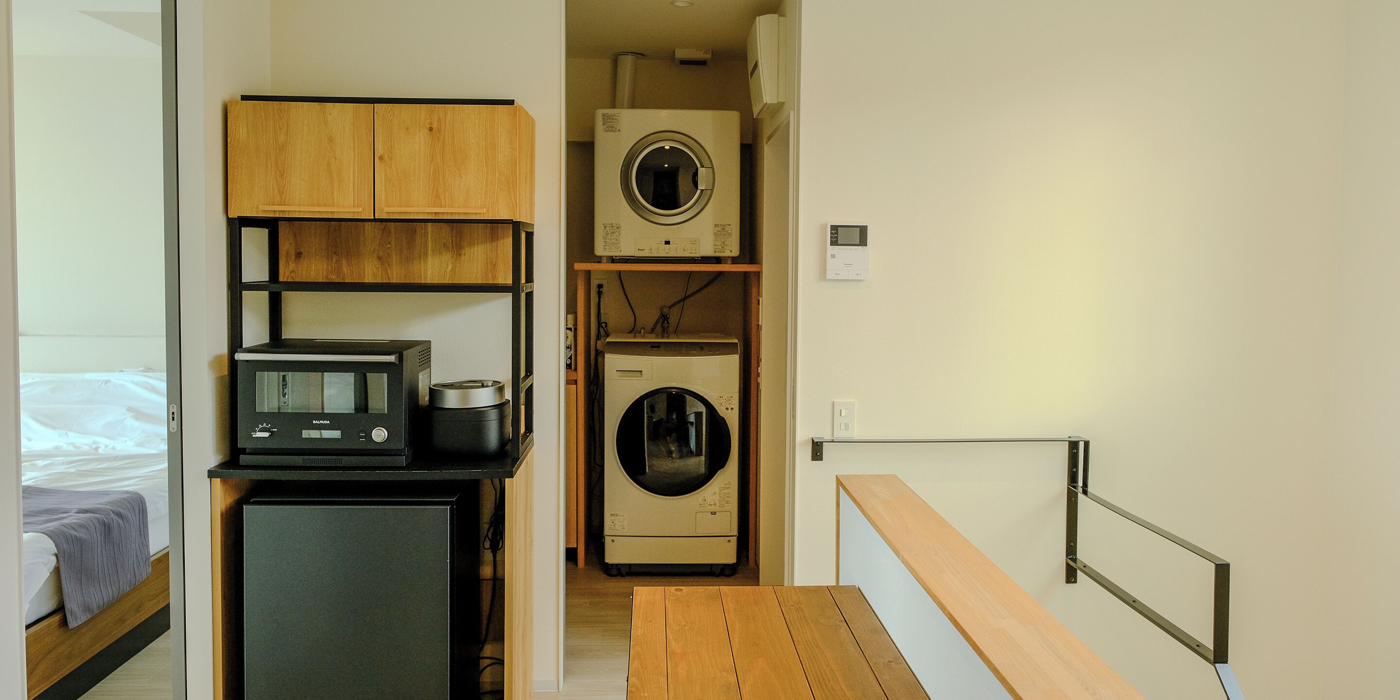 Una cocina compacta equipada con microondas, un refrigerador pequeño y una lavadora.