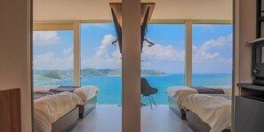 A bedroom with two beds, a large window, and a view of the sea. - VILLA MIKURI TSUNOSHIMA (Shimonoseki)
