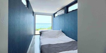 Una habitación pequeña con una cama, un ventanal y un equipo de aire acondicionado.