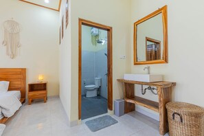 Et badeværelse med en trækommode, et spejl, en vask og et toilet.