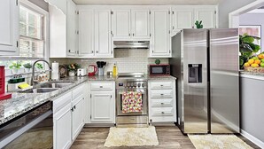 Una cocina moderna con armarios blancos, electrodomésticos de acero inoxidable y encimera de granito.