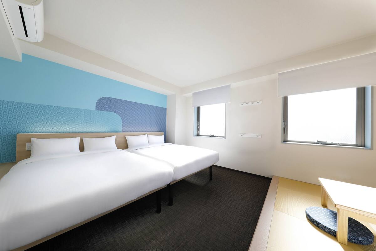 A hotel room with a bed, a desk, and a window.