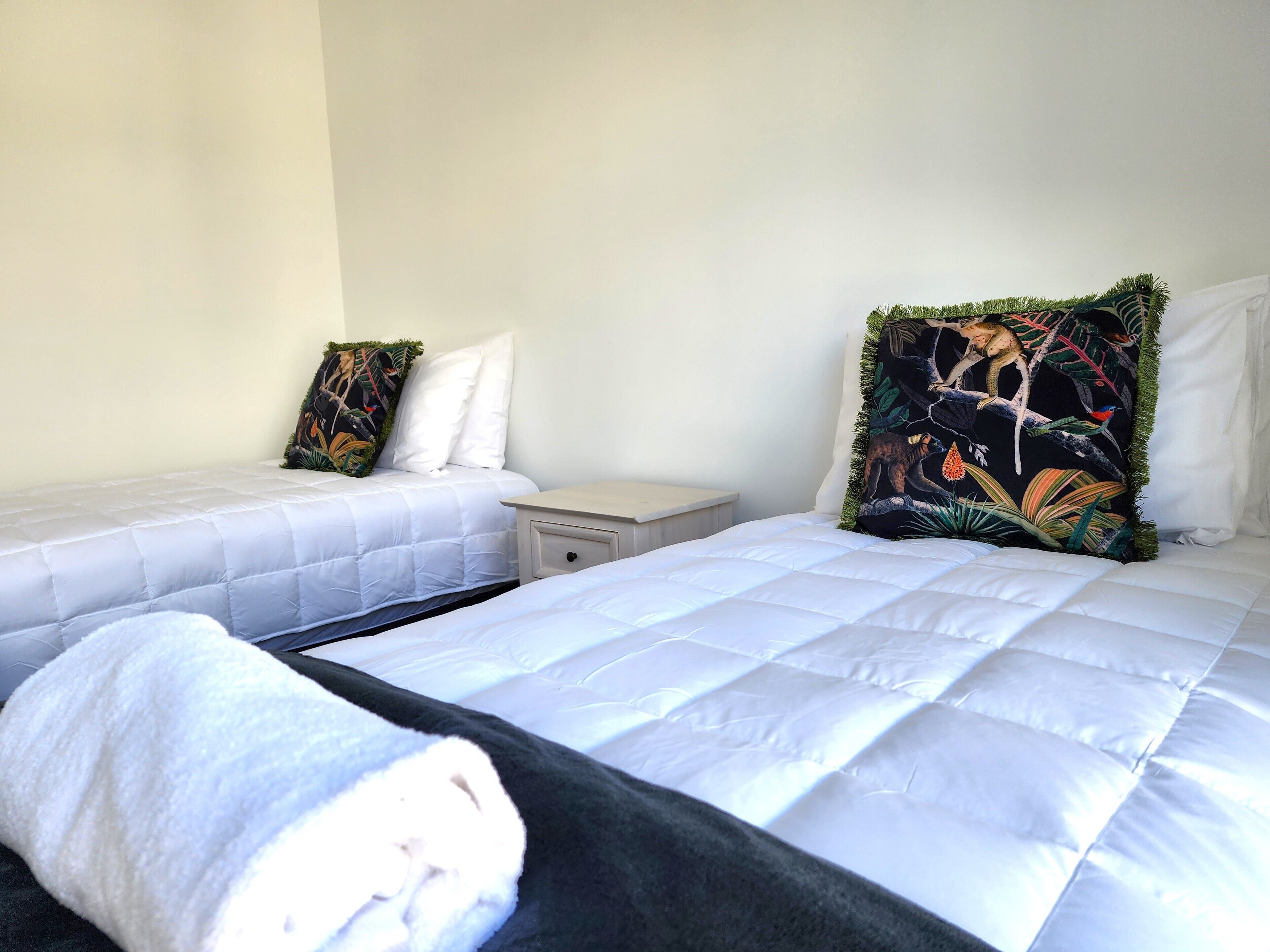 A hotel room with two beds, each with white bedding and a nightstand between them.