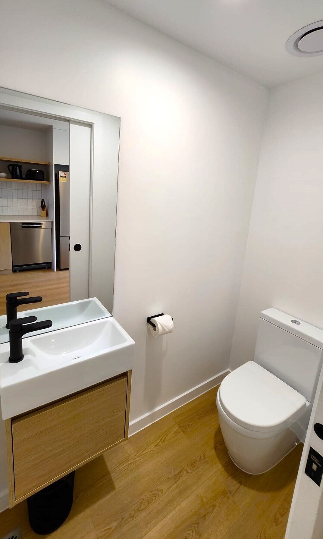 Un baño pequeño y moderno con lavamanos, inodoro y espejo sobre el lavamanos.