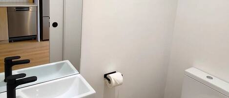 Un baño pequeño y moderno con lavamanos, inodoro y espejo sobre el lavamanos.
