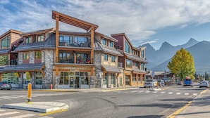A multi-story building with a stone facade, large windows, and a prominent entrance. - Best Views of Canmore - 2Bed 2Bath (Canmore)