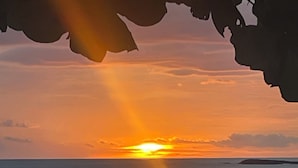 A sunset over a beach with calm waters and a few people walking along the shore. - Villa Zafiro: Luxurious private villa & pool - steps from gorgeous beaches! (Playa Langosta)