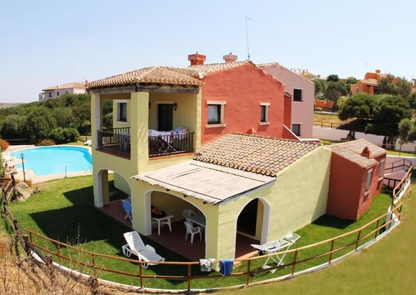 Une maison à deux étages avec une piscine, un patio couvert et une cour clôturée.