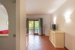 A compact living space with a kitchenette, a flat-screen TV, and a balcony with a table and chairs. - Charming Sea & Villas Villa V4IN no2091 (Sardegna)