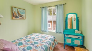 Quarto com cama, cómoda, janela com cortinas, quadro na parede e luminária no teto.
