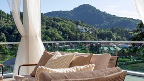 A balcony with wicker furniture and a view of a mountainous landscape. - Luxury Matahari Seaview (Kamala)