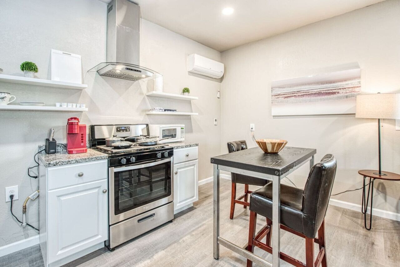 Una cocina moderna con estufa a gas, microondas y horno. Hay una mesa de comedor con sillas y una cafetera sobre la encimera.