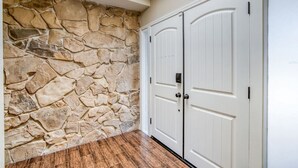 A room with a stone wall, wooden flooring, and white double doors.
