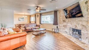 A living room with a stone fireplace, leather sofas, a coffee table, and a ceiling fan.