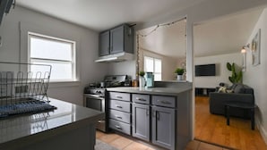 Una cocina moderna con armarios grises, estufa integrada y un área de comedor con sofá gris y una pequeña mesa.