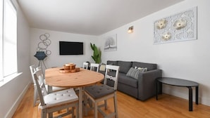 Una sala de estar moderna con una mesa redonda de madera, un sofá gris y una pequeña mesa negra.