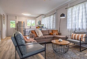 En moderne stue med sofa, sofabord og et spiseområde med stole.