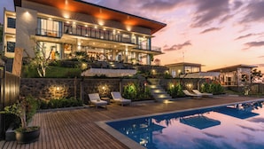 A modern multi-story house with a swimming pool, outdoor seating, and a well-lit balcony. - Villa Lovina Hill Paradise (Banjar)