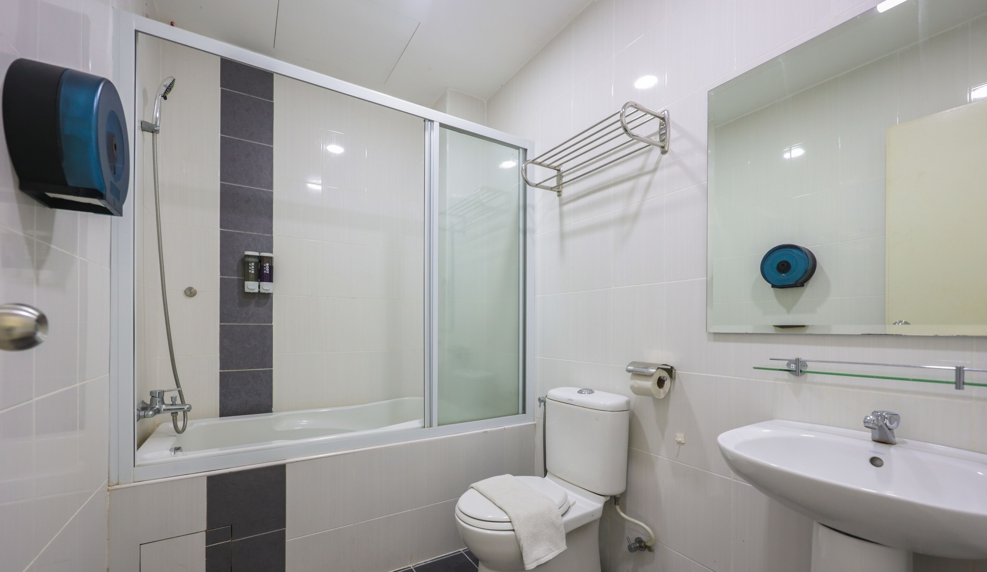 Uma casa de banho moderna com cabine de duche de vidro, sanita, lavatório e espelho.