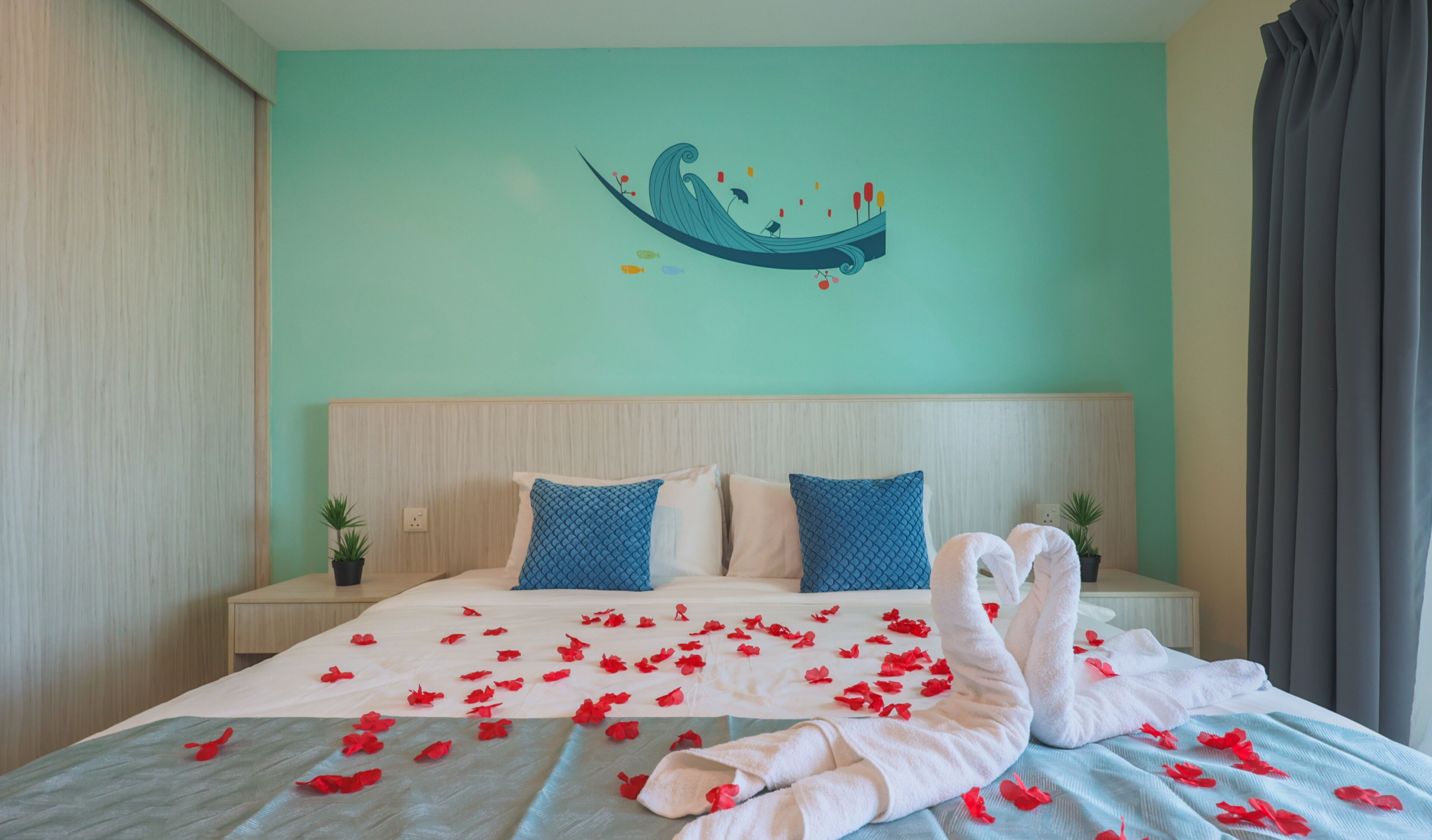 A hotel room with a bed, two pillows, a wall art piece, and a window with curtains.