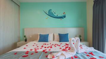 A hotel room with a bed, two pillows, a wall art piece, and a window with curtains.