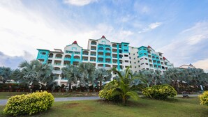 A multi-story hotel with a symmetrical facade, multiple balconies, and a central red roof.