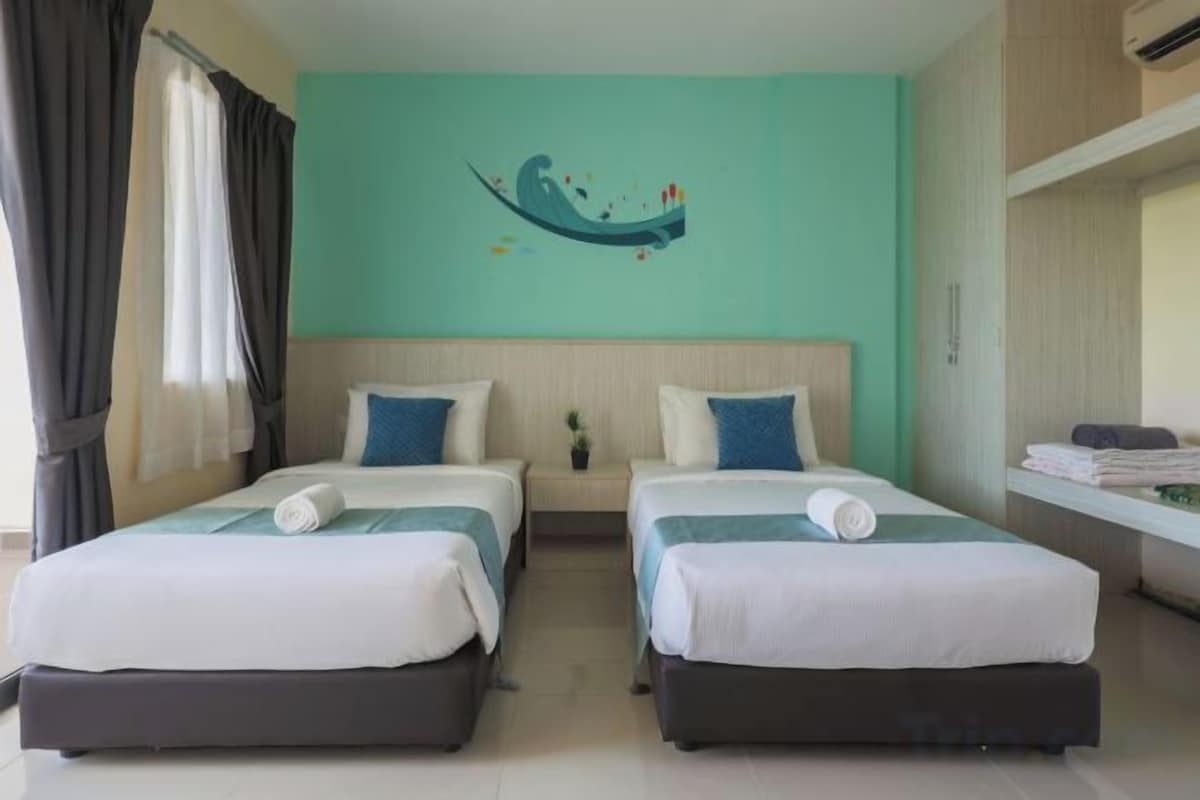 A hotel room with two beds, a teal wall, and a decorative wall art piece.
