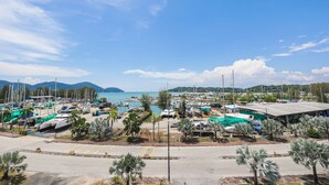 Un port de plaisance avec des bateaux amarrés, des palmiers et une vue sur la mer et les montagnes.