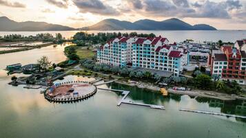 Un hotel con varias edificaciones, un puerto deportivo y un lago con montañas al fondo.