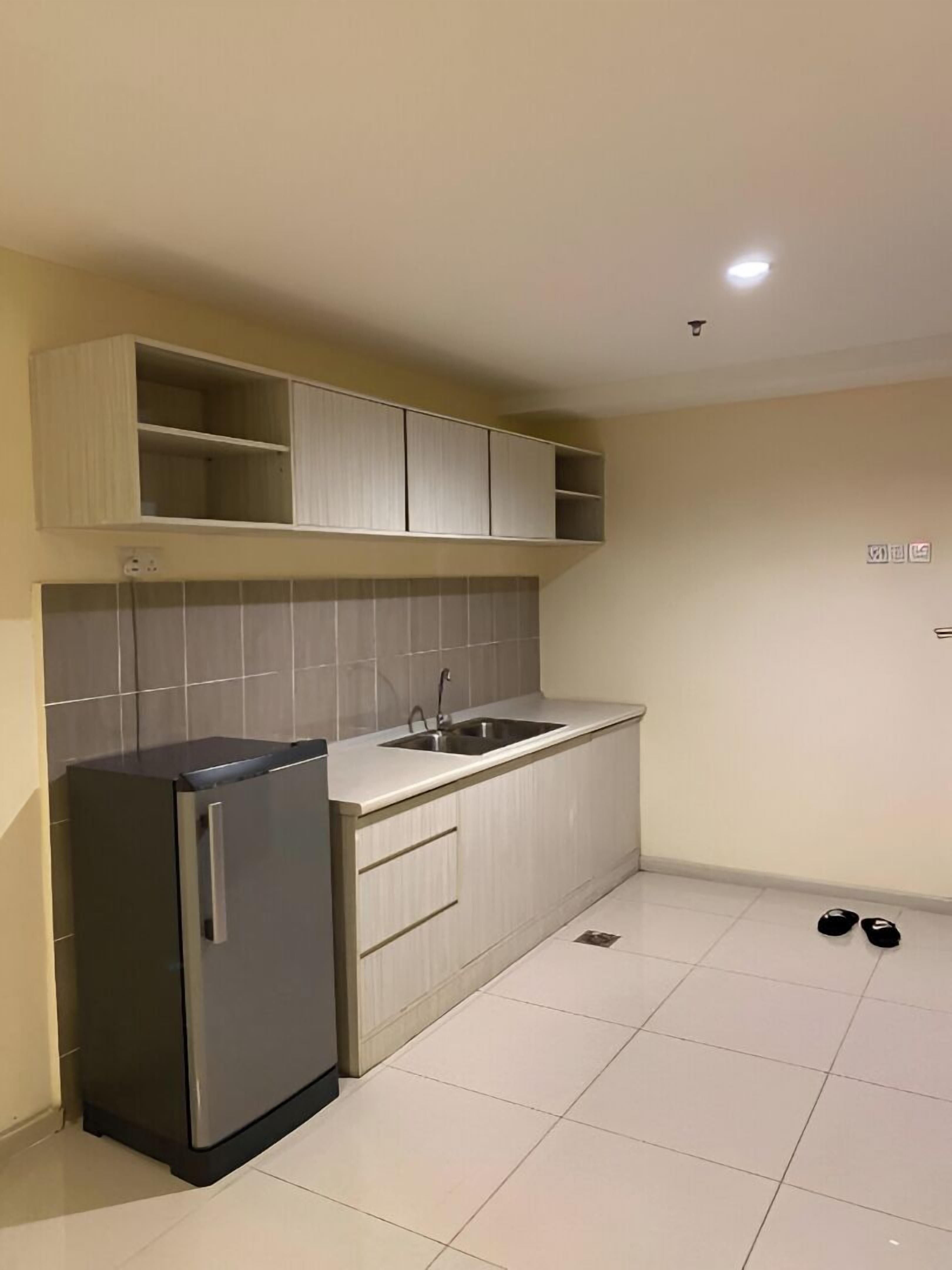 Una cocina compacta con refrigerador integrado, un lavamanos y gabinetes superiores.