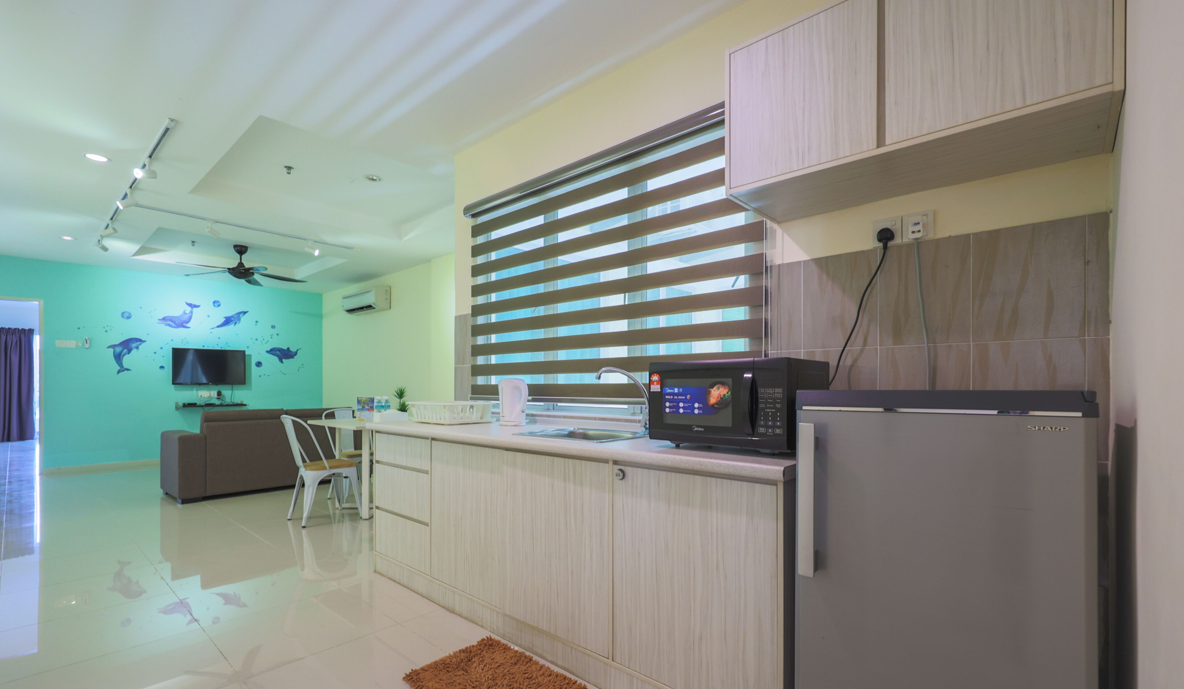 Una cucina moderna con microonde, frigorifero e zona pranzo con divano e sedie.