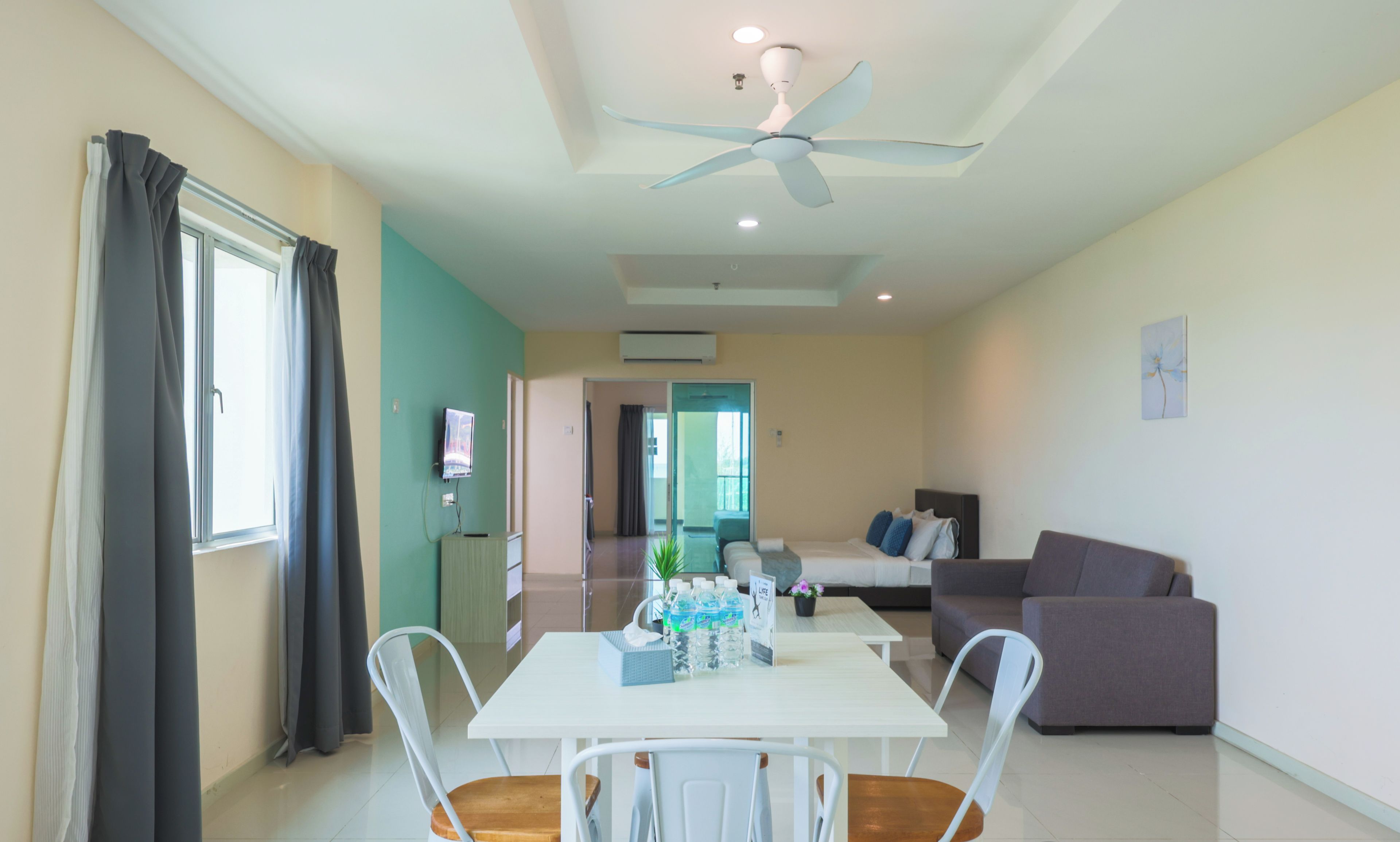 A modern living room with a dining area, a ceiling fan, and a view into another room.