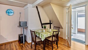 A dining area with a table set for four, a clock on the wall, and a door leading outside. - Apartment 'Ferienwohnung 2' with Wi-Fi (Ubstadt-Weiher)