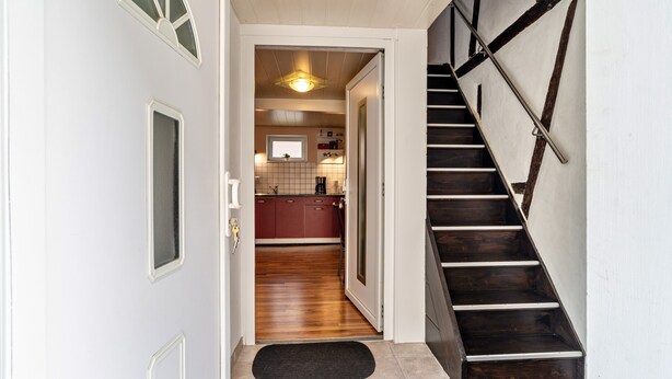 A staircase with wooden steps and metal handrails, leading to a kitchen area with wooden flooring and a window. - Apartment 'Ferienwohnung 2' with Wi-Fi (Ubstadt-Weiher)