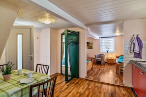 Un espacio habitable compacto con comedor, kitchenette y dormitorio.